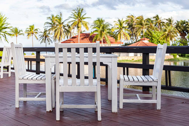 White wooden dining table by the pool inside the resort - Фото, изображение