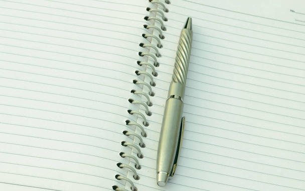 Close up of pen placed on spiral notebook. Full frame shot. High angle view. Business education background. - Photo, Image