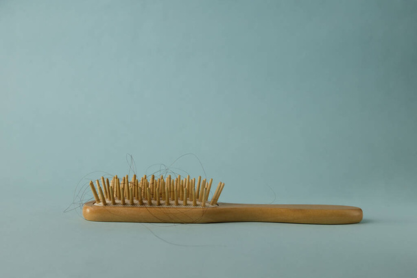 Una spazzola per capelli in legno con capelli su sfondo azzurro con spazio copia - Foto, immagini