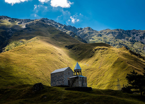 Nyári táj Kazbegiben: kaukázusi hegyek és Szent Ilja Ortodox templom (Ioane Natlismcemeli) Stepantsmindában, Grúziában - Fotó, kép