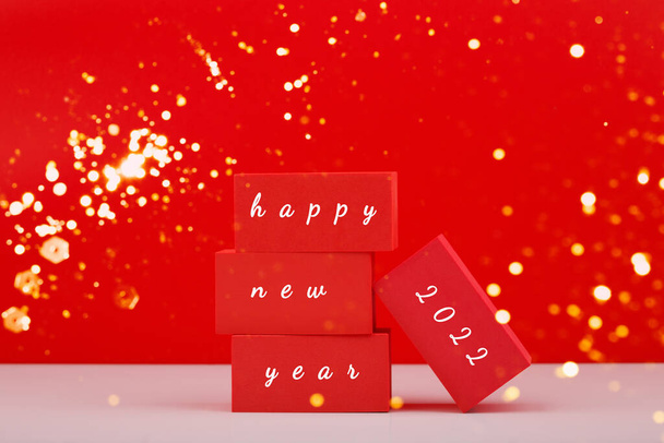 Happy New Year red minimal trendy concept. Modern festive composition with red toy blocks with written Happy New Year 2022 text against red background - Photo, image