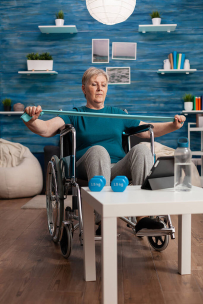 Donna anziana concentrata in abbigliamento sportivo guardando allenamento fitness online utilizzando tablet - Foto, immagini