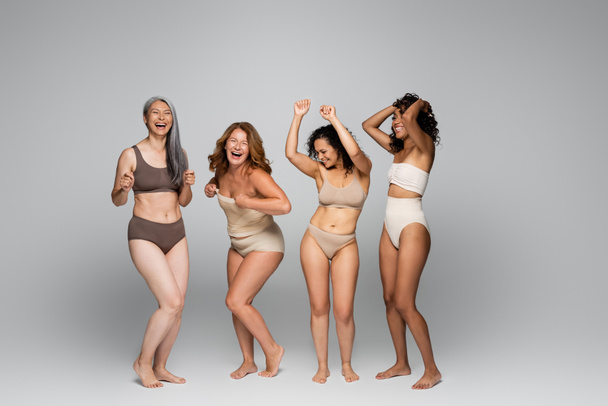 Positive interracial women in underwear on grey background  - Fotó, kép