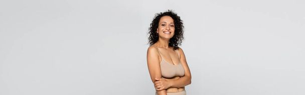 Cheerful african american woman in bra looking at camera isolated on grey, banner  - Photo, Image