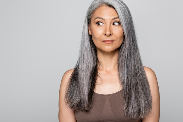 Grey haired asian woman in bra looking away isolated on grey - Foto, imagen
