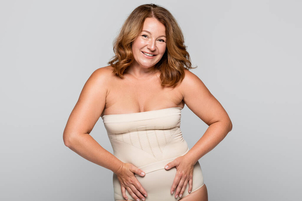 Smiling woman in underwear looking at camera isolated on grey, body positive concept - Foto, Bild