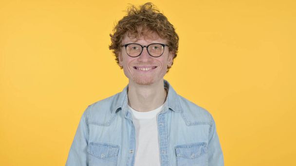 Lächelnder Rotschopf junger Mann auf gelbem Hintergrund - Foto, Bild