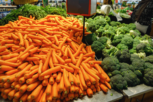 Haufen frischer Möhren und Brokkoli auf der Ladentheke im Supermarkt - Foto, Bild