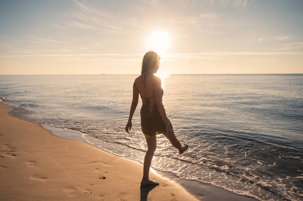 Hermosa joven asiática mujer en traje de baño disfrutando y salpicando en la playa en el mar tropical por la mañana - Foto, Imagen
