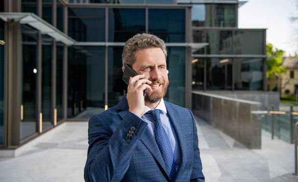 wesoły przedsiębiorca w garniturze biznesowym prowadzi rozmowy telefoniczne poza biurem, negocjacje - Zdjęcie, obraz