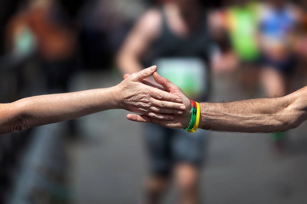 La stretta di mano solidale nello sport. Supporto durante lo sforzo fisico della gara di un atleta che corre la maratona. - Foto, immagini