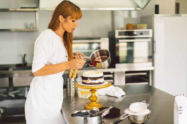 Konditorin bereitet Kuchenkekse mit weißer Sahne und Schokolade zu. Kuchen backen. - Foto, Bild