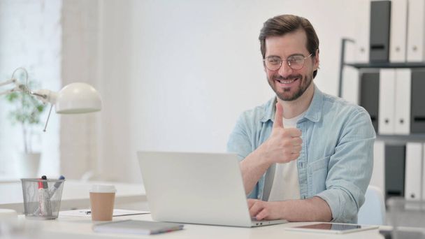 Thumbs Up by Young Man with Laptop at Work - Фото, изображение