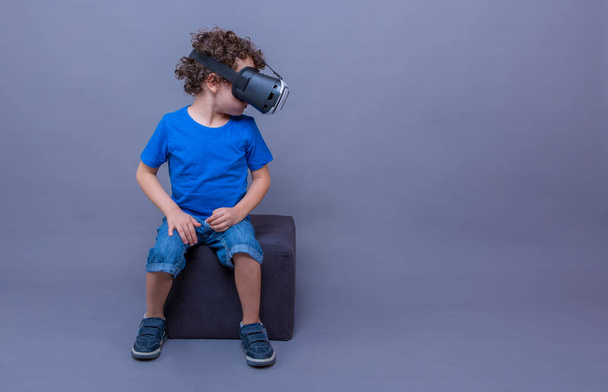 παιδί κάθεται και παίζει με γυαλιά εικονικής πραγματικότητας, - Φωτογραφία, εικόνα