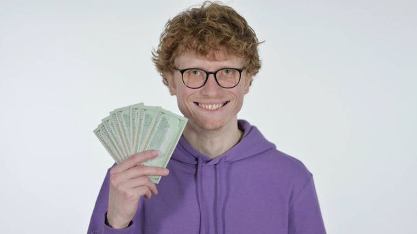 Rudowłosy młody człowiek licząc dolary na białym tle - Zdjęcie, obraz