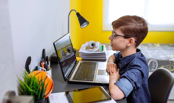 Çocuk, yatak odasındaki dizüstü bilgisayarla evde ders alıyor. - Fotoğraf, Görsel