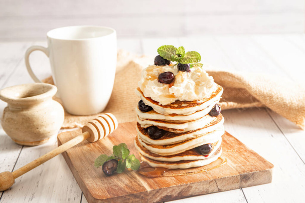 Ένα πακέτο φρεσκομαγειρεμένες τηγανίτες με βατόμουρα σε λευκό φόντο, πρωινό γεύμα - Φωτογραφία, εικόνα