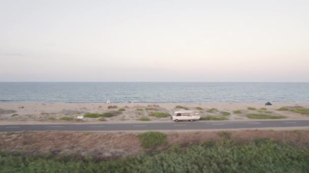 Drone latający obok pustej plaży drogi z zaparkowanych przyczep turystycznych w pobliżu plaży piasku - Materiał filmowy, wideo