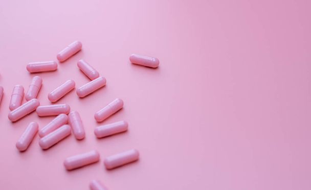 Comprimidos cápsulas rosa espalhados sobre fundo rosa. Vitamina e suplemento para pele saudável e acne conceito. Farmácia online. Banner da farmácia. Indústria farmacêutica. Receita de tratamento de amor.  - Foto, Imagem