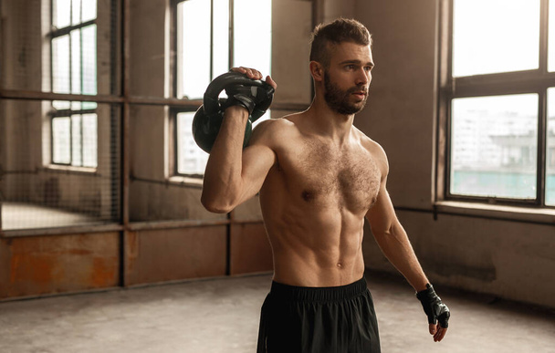 Shirtless man working out with kettlebell - Foto, Imagen