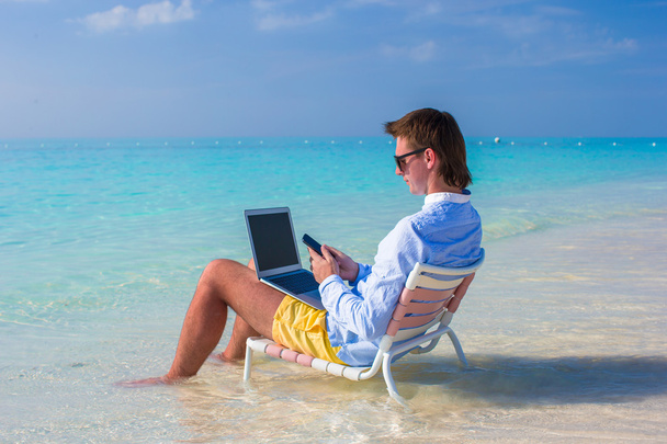 Hombre joven usando portátil en la playa tropical
 - Foto, Imagen