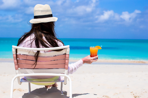 Takaisin näkymä nuori pitkäkarvainen nainen cocktail kädessä ja olki hattu rannalla
 - Valokuva, kuva