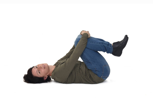 mujer acostada en el suelo de rodillas sosteniendo y mirando a la cámara sobre fondo blanco - Foto, Imagen