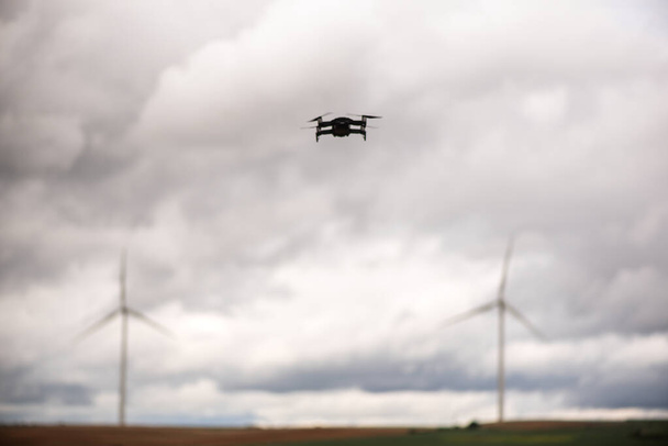 Selektive Fokusaufnahmen von Drohnen, die auf einem Feld nachhaltiger Windkraftanlagen fliegen. - Foto, Bild