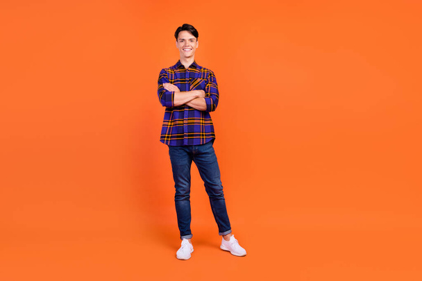 Full length photo of millennial nice guy stand crossed arms wear shirt jeans sneakers isolated on orange background - Foto, Imagen