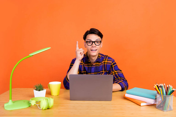 Photo of young cool guy type laptop point up wear checkered shirt spectacles isolated on orange background - Foto, Imagen