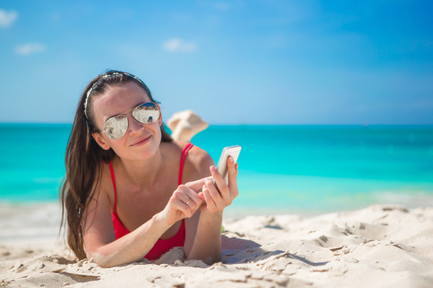 młoda kobieta z jej telefon na egzotycznej plaży - Zdjęcie, obraz