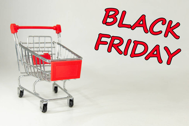 Black Friday 2021. Design for Black Friday accompanied by a metal shopping cart for the huge sales on these dates. White background. Space for text. Horizontal photography. - Foto, Imagen