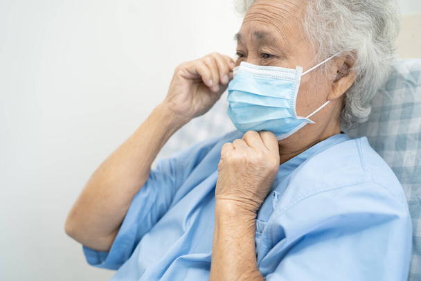Paciente de edad avanzada o anciana asiática que usa una mascarilla facial nueva normal en el hospital para proteger la infección de seguridad Covid-19 Coronavirus. - Foto, imagen