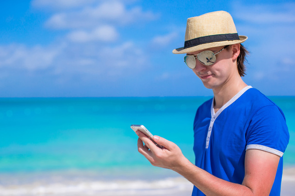 Joven hombre de negocios con su teléfono en vacaciones en la playa
 - Foto, imagen