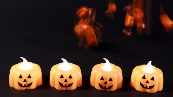 Vorbereitungen für Halloween. Orangefarbene Bonbons ergießen sich über den schwarzen Hintergrund, Kürbislaternen leuchten. - Filmmaterial, Video