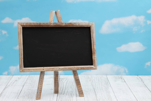 Blank standing chalkboard on weathered wood with clear sky with copy space for your message - Fotoğraf, Görsel