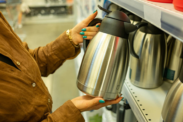 Woman chooses an electric kettle in a store - Foto, afbeelding