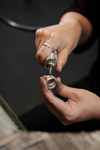 Female hands of bench jeweler forming silver ring using polisher in workshop - Zdjęcie, obraz