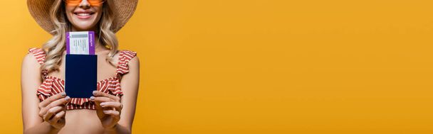 vista cortada de mulher alegre no topo do biquíni ruffle segurando passaporte com bilhete de ar isolado no amarelo, banner - Foto, Imagem