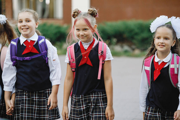 Group of children in school uniforms with backpacks go to school. Selective focus, blurred background. Primary School. - Photo, Image