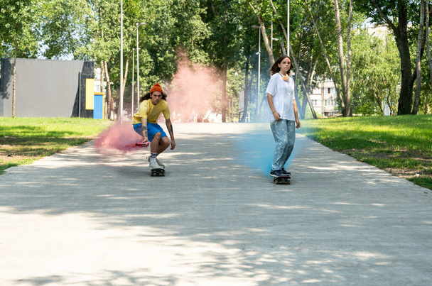 skaters with colored smoke bombs. Professional skateboarders having fun at the skate park - Foto, imagen