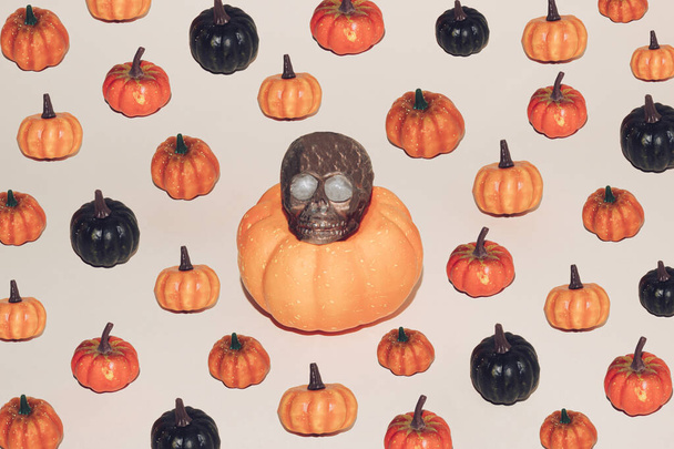 Halloween minimal concept with colorful pumpkins and brown skull. Creative spooky holiday fun background. Santa Muerte concept. Autumn backdrop. - Photo, Image