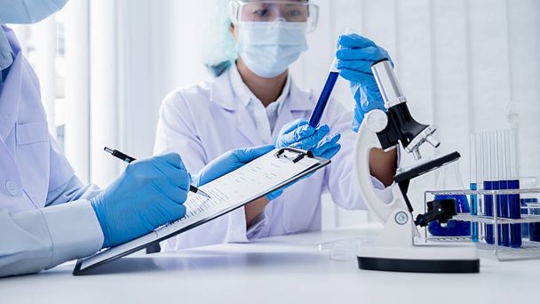 Investigador médico o científico o médico de cabecera mirando un tubo de ensayo de solución transparente en un laboratorio - Foto, imagen