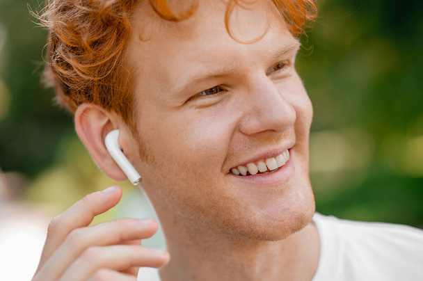 Joyous man with a wireless earbud looking into the distance - Photo, Image