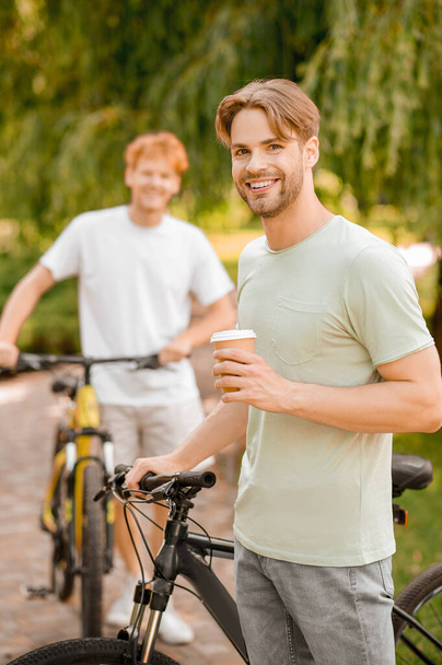 Dos ciclistas disfrutando de su descanso para tomar café juntos - Foto, Imagen