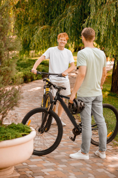 Задоволений велосипедист розмовляє зі своїм другом на відкритому повітрі
 - Фото, зображення