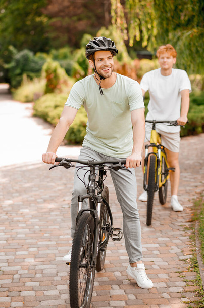 Contented bicyclist and his pal riding bikes outdoors - Photo, Image