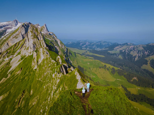 A woman with a backpack stands on top of a mountain , The girl travels to beautiful places, Reaching the goal, mountain ridge at Saxer Luecke , Kreuzberge in Alpstein Appenzell Innerrhoden Switzerland - Photo, Image