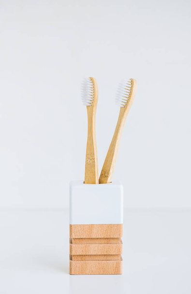 Bamboo toothbrushes in a wooden cup making with natural materials, isolated on white background - Photo, image