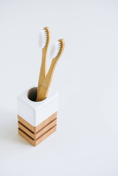 Bambus-Zahnbürsten in einer hölzernen Tasse aus natürlichen Materialien, isoliert auf weißem Hintergrund - Foto, Bild
